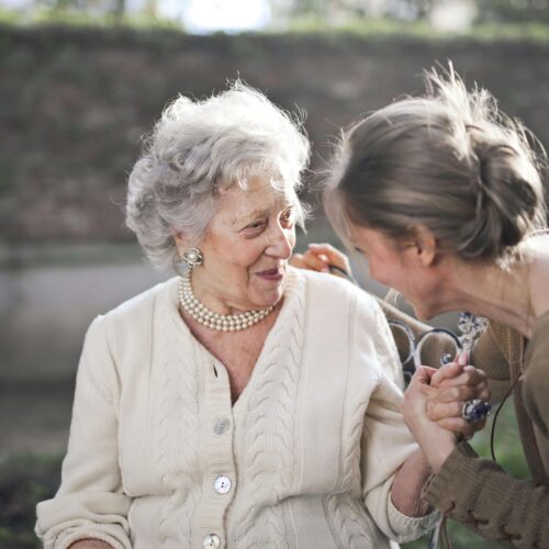 Young woman comforting an elderly woman in nature, symbolising a peaceful farewell and affordable direct cremation service.